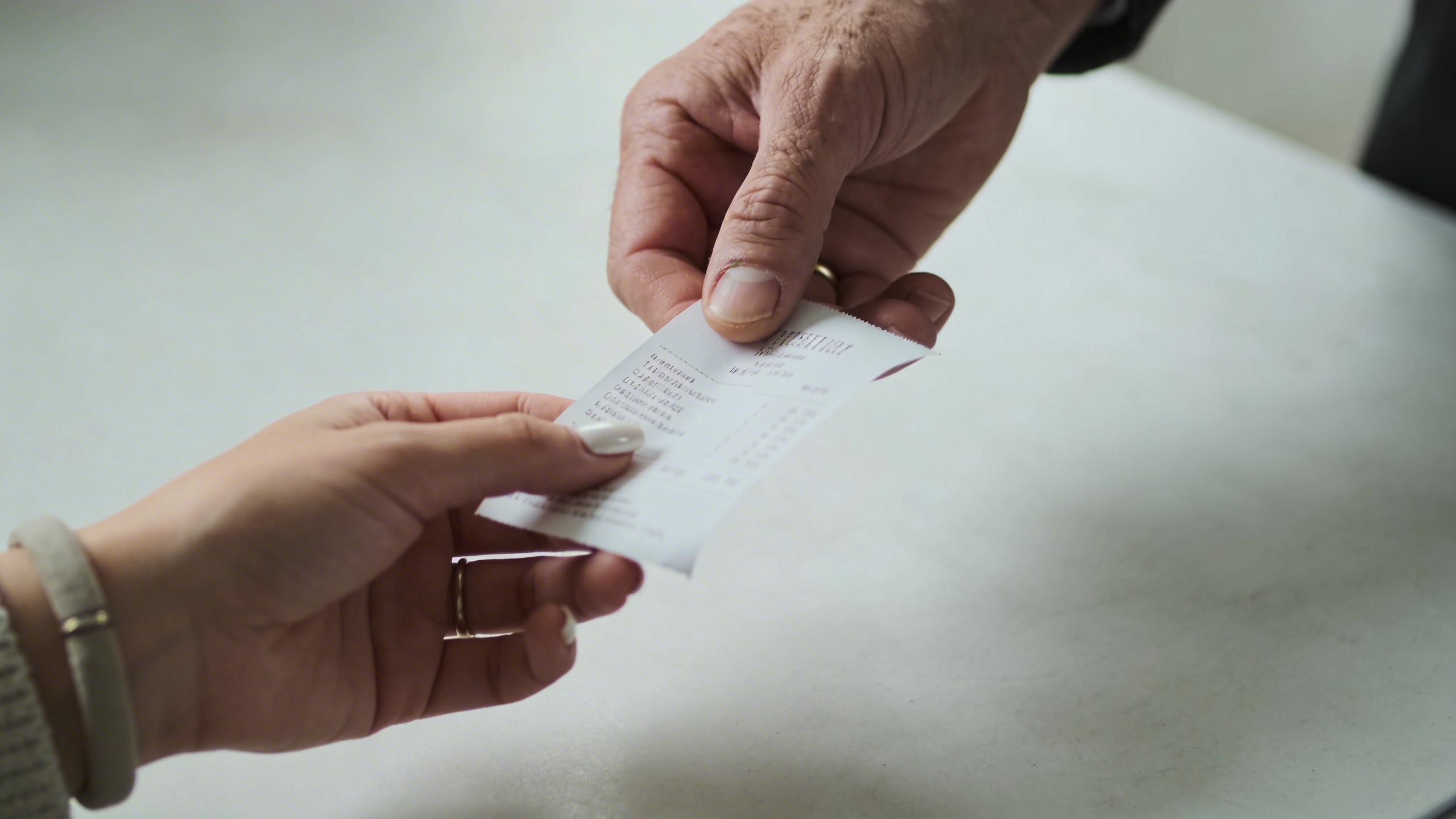 Main de commercant tendant un ticket de caisse a un client