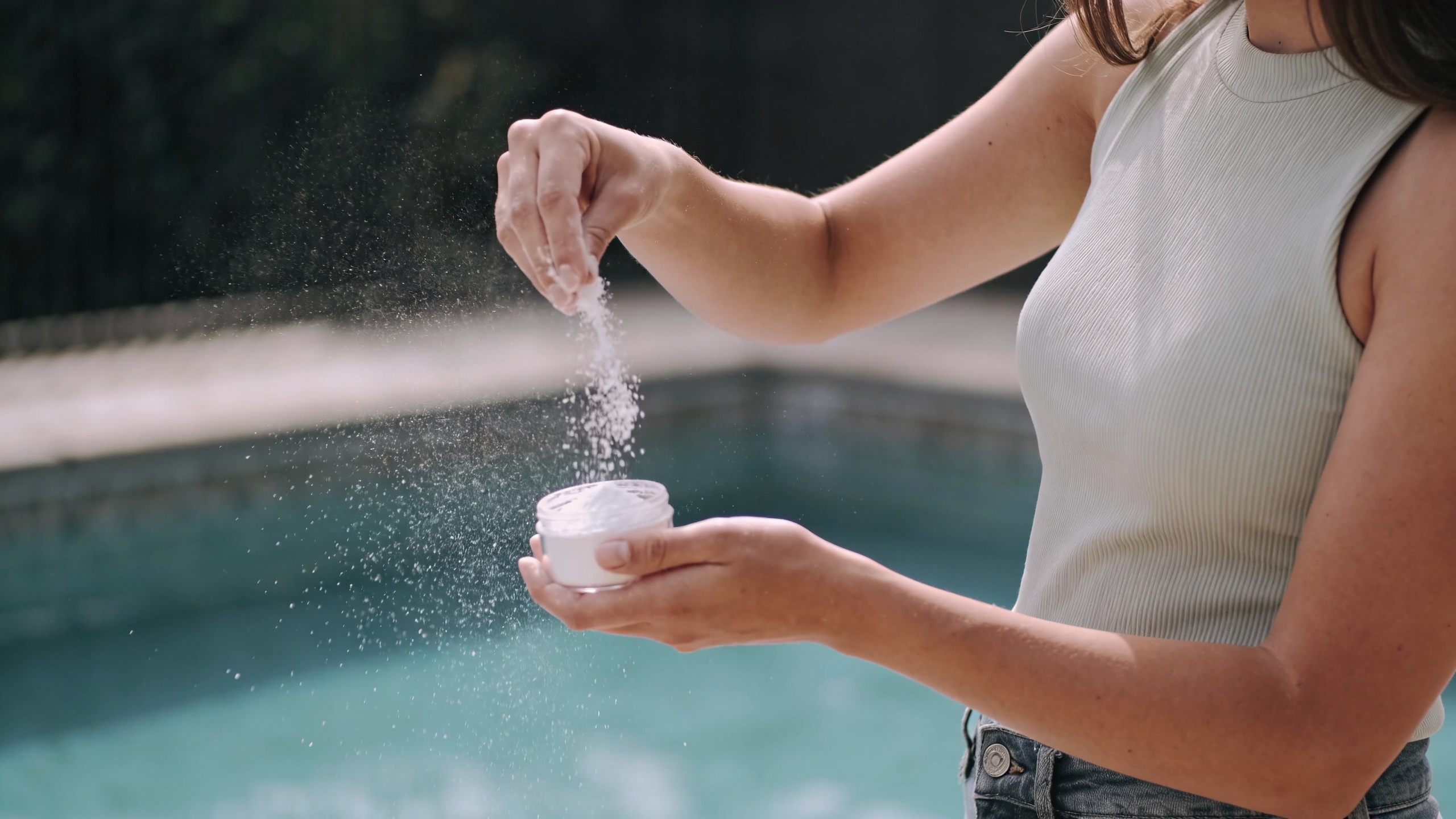 Femme verse du bicarbonate autour dune piscine extérieure