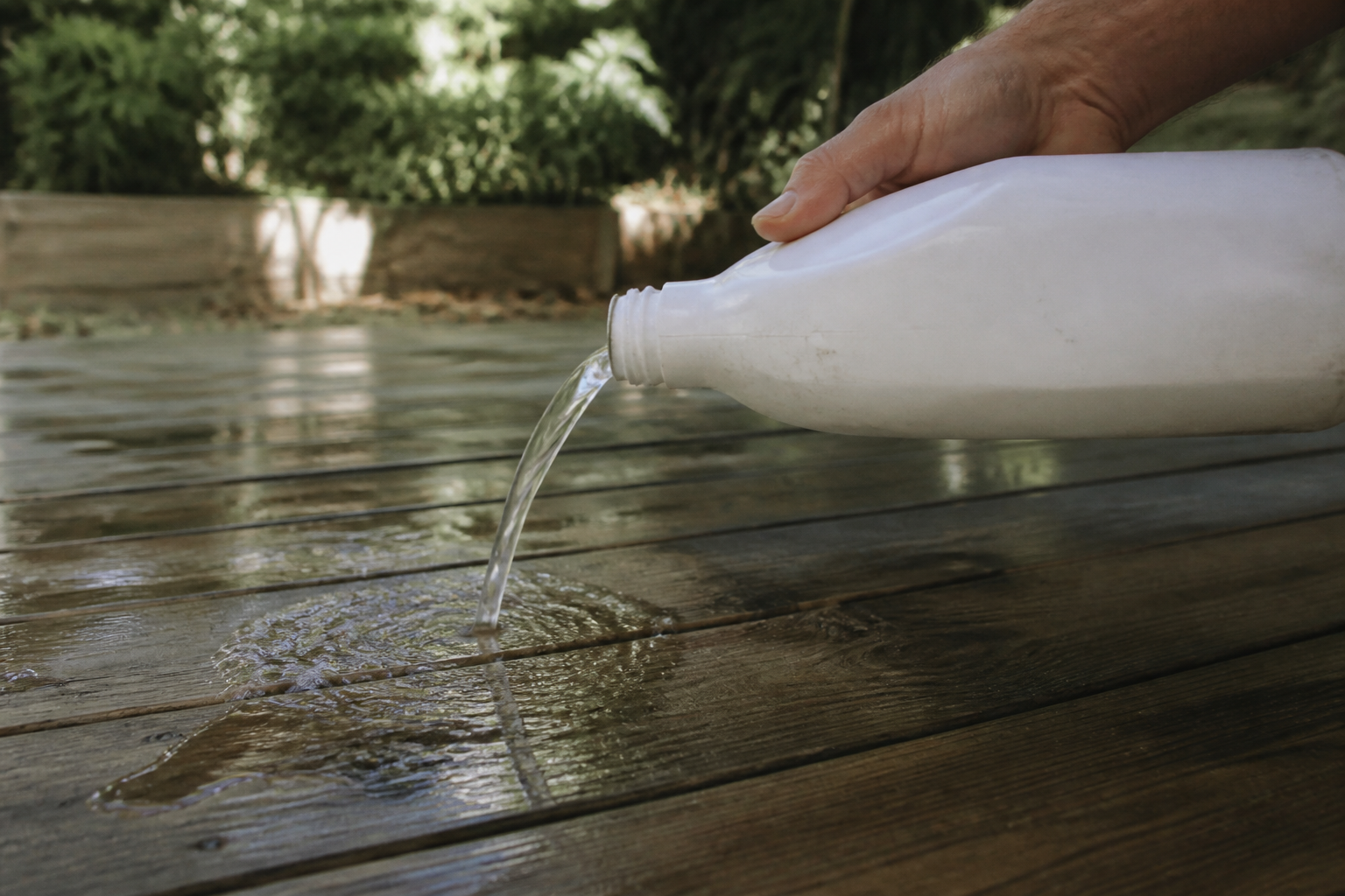 Bouteille de nettoyant versée sur planches bois horizontales mouillees