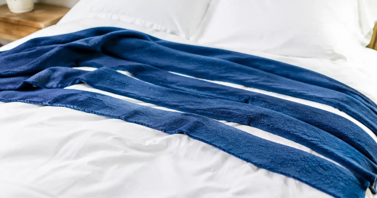 Couverture polaire decoupee en bandes posee sur un lit blanc