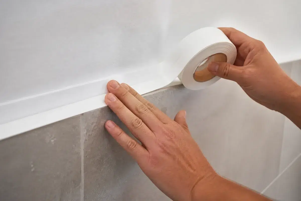 Mains posant une bande adhesive blanche murale