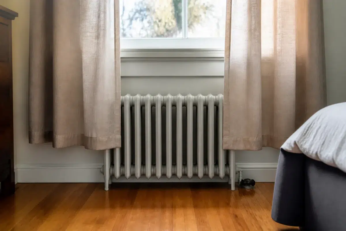 Rideau court devant radiateur sous fenetre laissant espaces vides