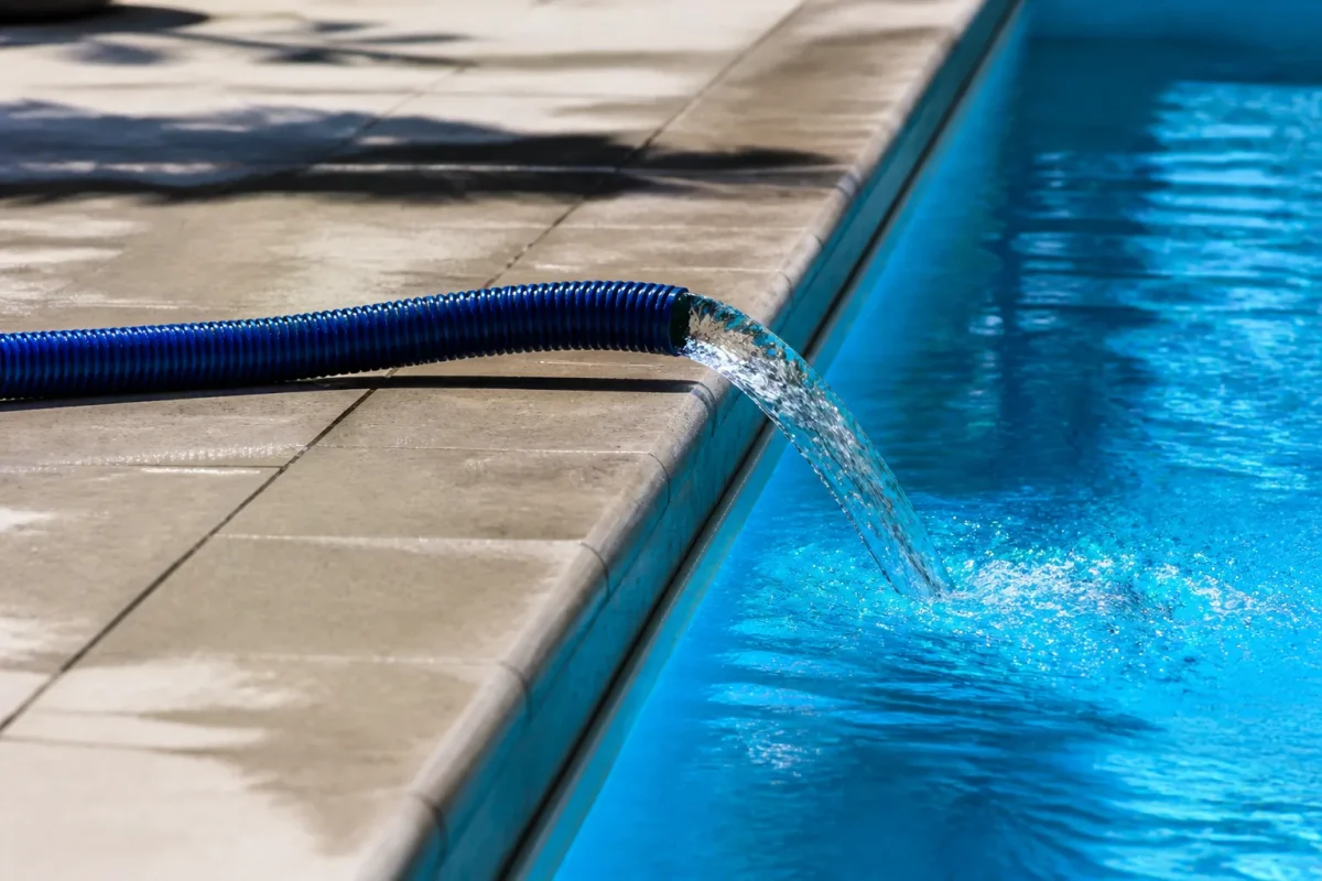 Eau bleue s'echappant d'une piscine par un tuyau