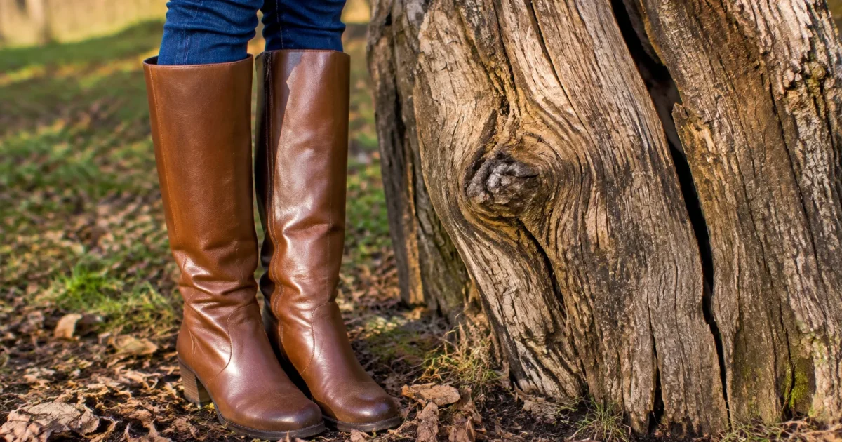 Femme en bottes debout devant un tronc noueux fendu